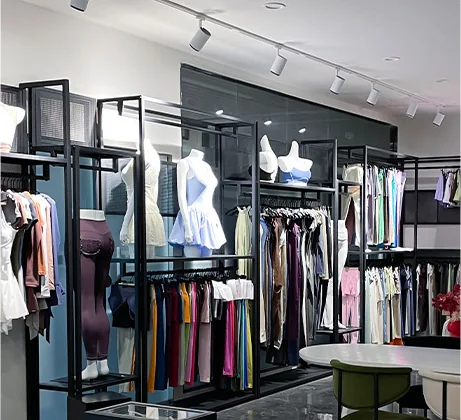 A showroom with black open-frame racks of hanging apparel, mannequin torsos and a display table